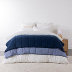 Blue: Navy and soft blue two-tone quilted blanket layered across a neatly styled bed.