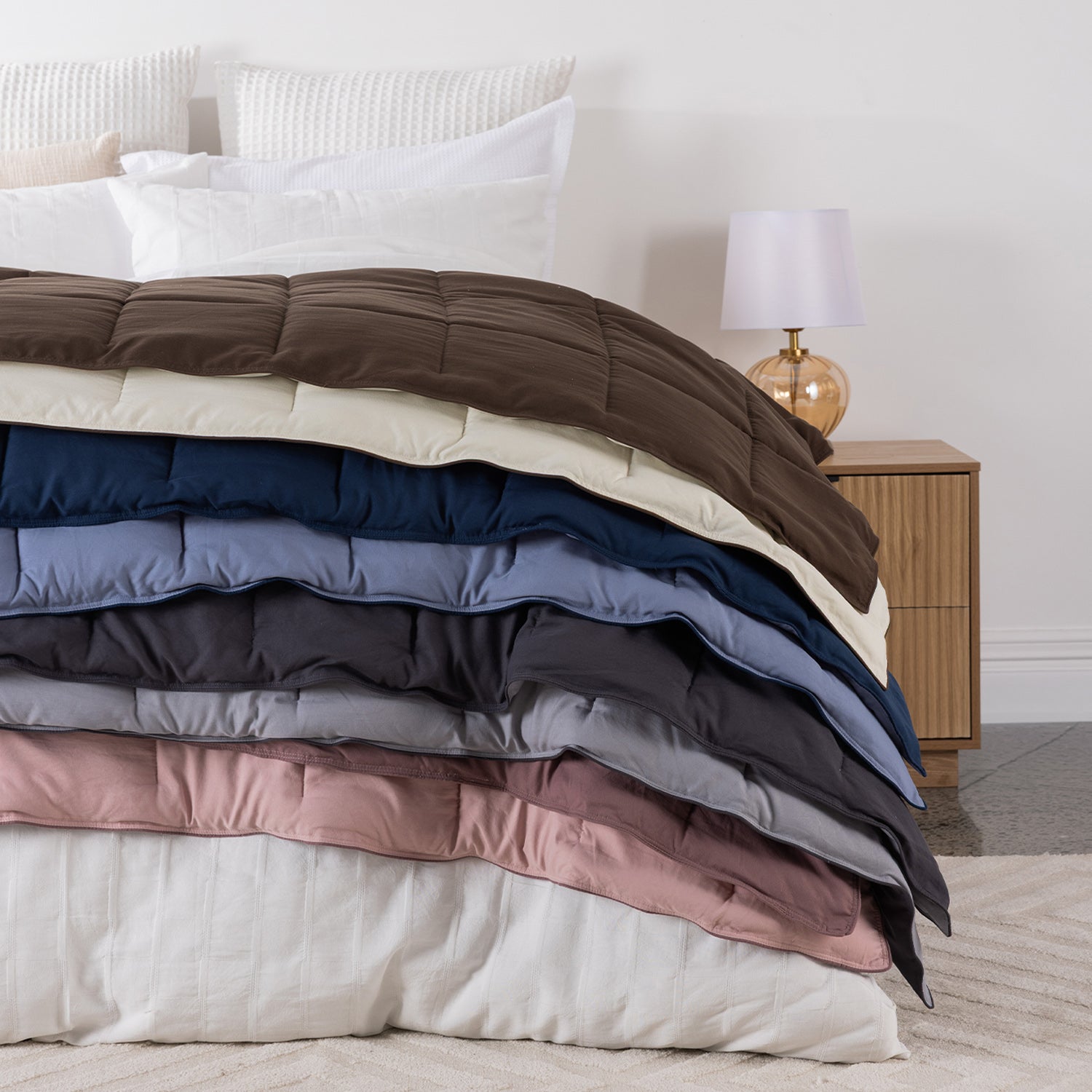 Stack of soft quilted blankets layered across a neatly styled bed.