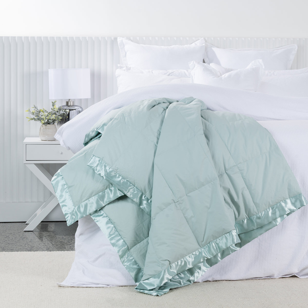 Fieldcrest Duck Down Blanket in Duckegg draped across a white bed, featuring quilted panels and a coordinating satin border.