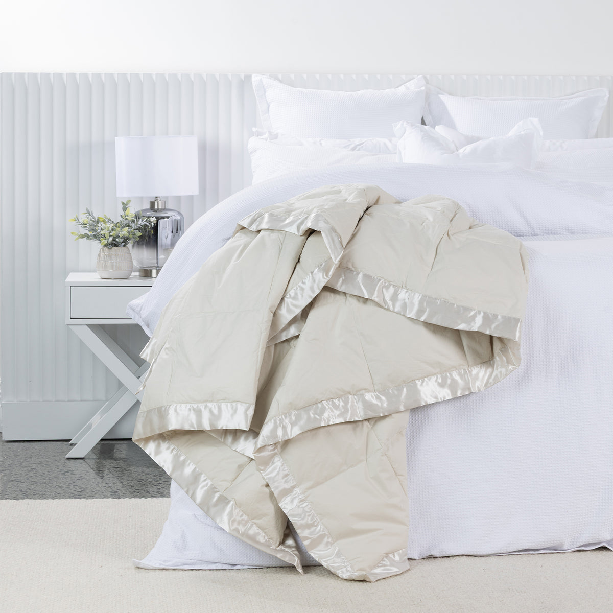 Fieldcrest Duck Down Blanket in Natural draped across a white bed, featuring quilted panels and a coordinating satin border.