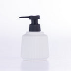 White ribbed bathroom soap dispenser with a contrasting black pump, displayed on a white background.