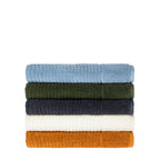 Side view of folded Fieldcrest Marney textured bath towels stacked in blue, green, charcoal, ivory, and caramel.