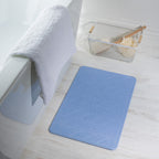 Mist stone quick dry bathmat featuring a modern geometric pattern, styled beside a bathtub in a bright contemporary bathroom setting.