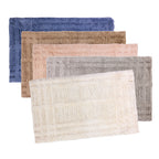 Five Fieldcrest Jenna Self Check tufted bath mats in Blue Smoke, Beige, Blush, Silver, and Ivory displayed in an overlapping group shot.