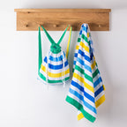 Striped kids hooded towel and matching bag hanging on wooden hooks.
