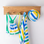 Striped kids hooded towel and matching bag and hat hanging on wooden hooks.