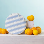 A round  2 person picnic set on a white wooden table, styled with lemons and oranges against a light blue background.