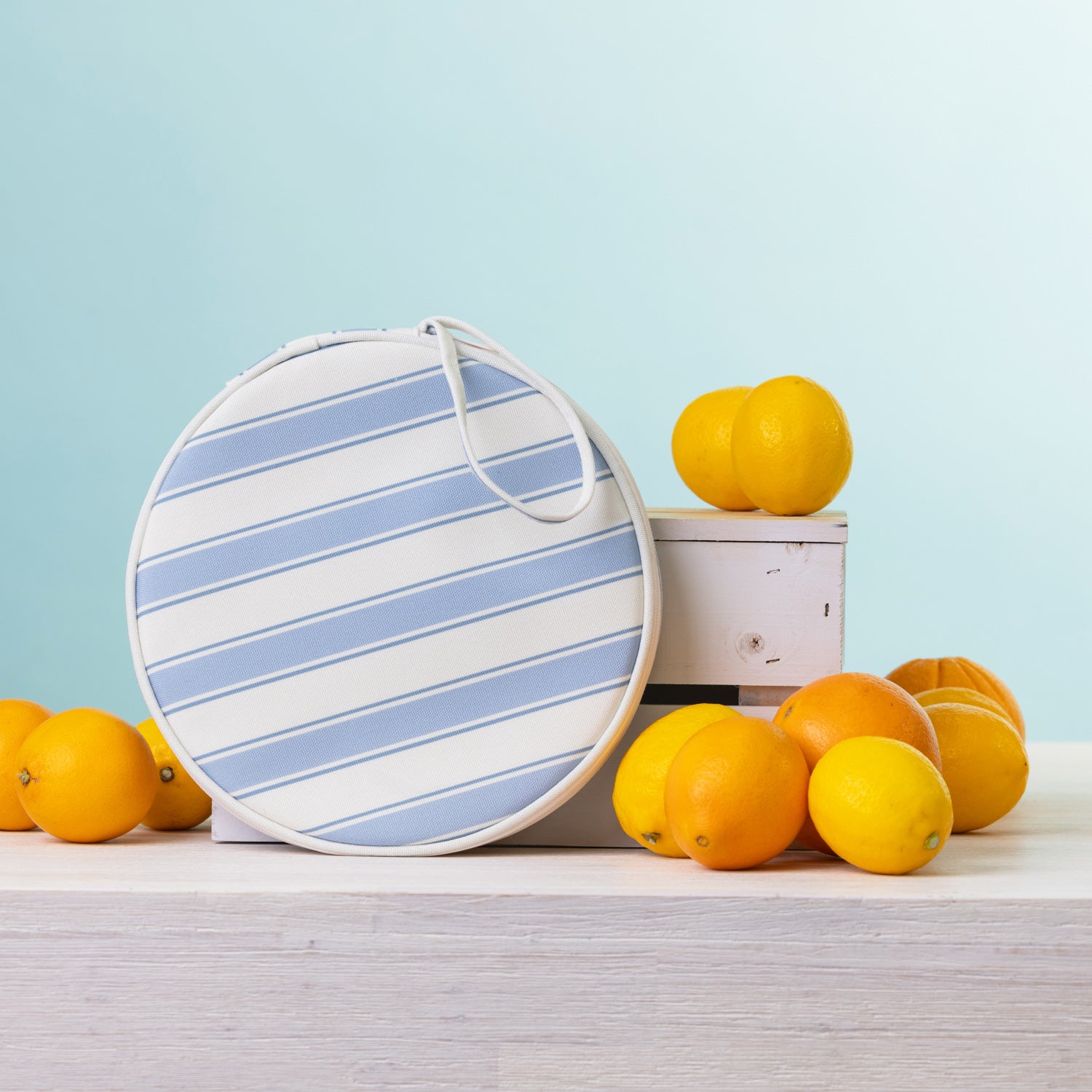A round  2 person picnic set on a white wooden table, styled with lemons and oranges against a light blue background.