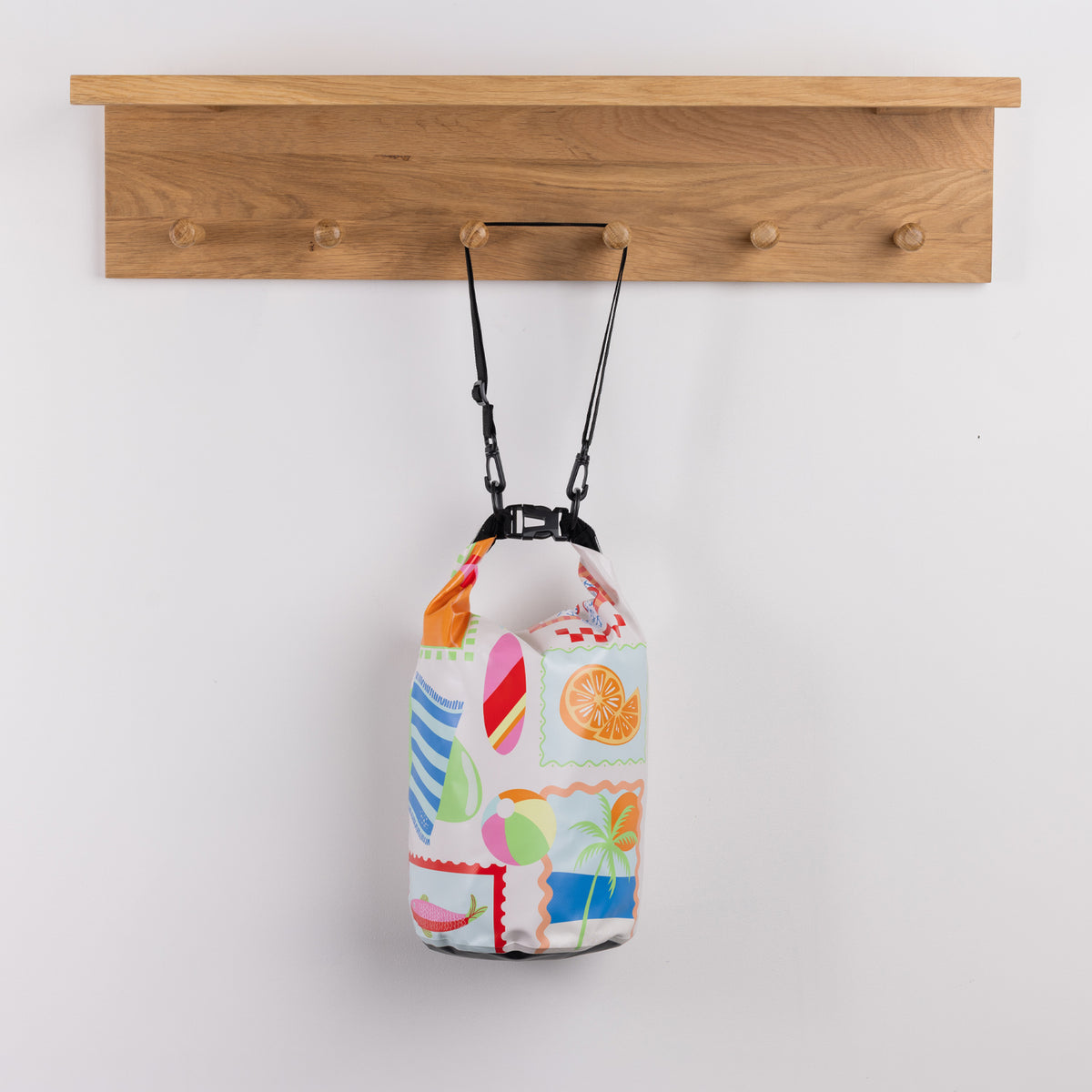 Seaside Supplies Waterproof Beach Bag 8L Sunny Days featuring a playful multicoloured beach-themed print with palm trees, citrus fruit, beach balls and colourful patterns.
