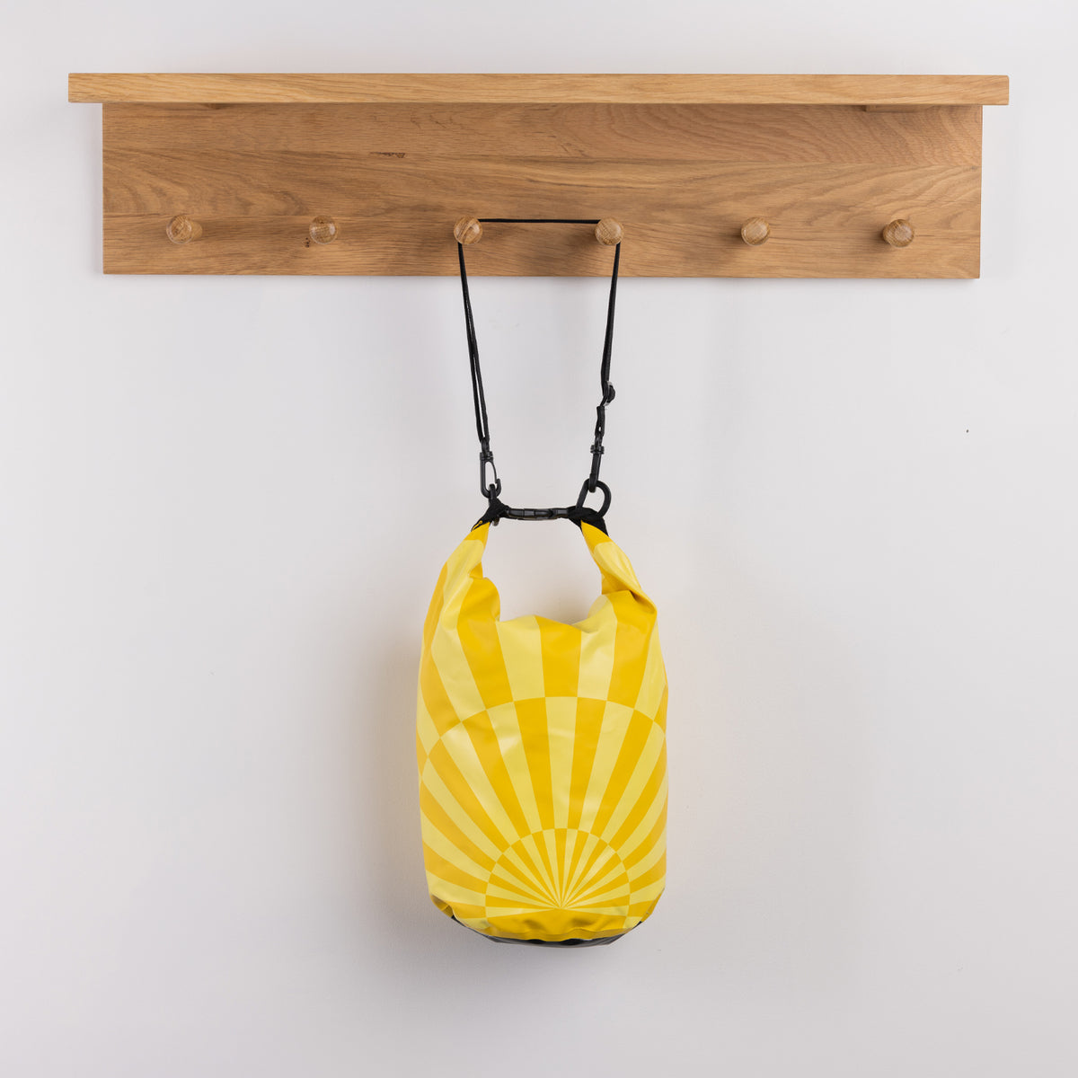 Seaside Supplies Waterproof Beach Bag 8L Sunrise Yellow featuring a bright yellow sunburst design with a roll-top closure, black buckle fastening and adjustable shoulder strap.