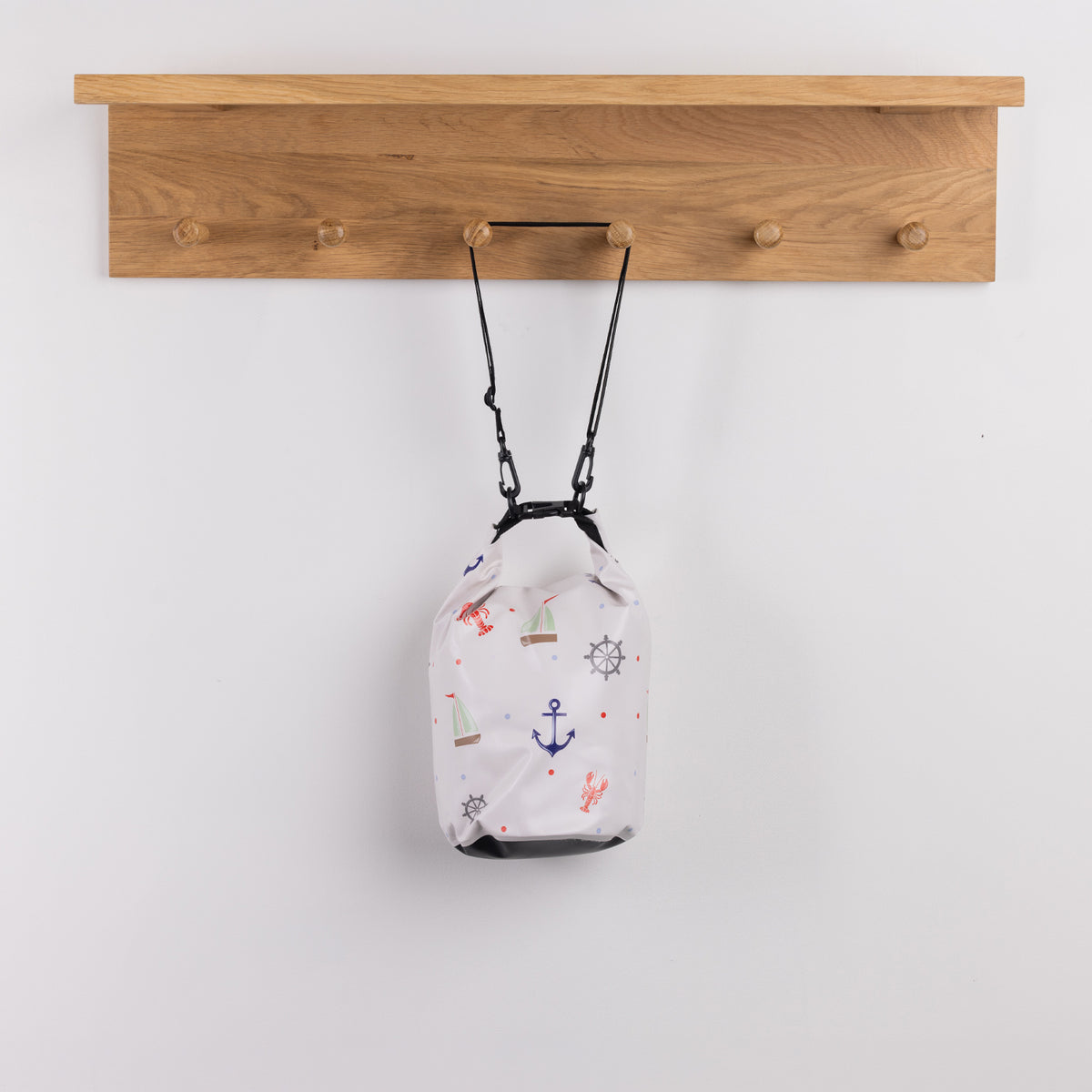 Seaside Supplies Waterproof Beach Bag 5.8L Sailor featuring a white background decorated with colourful nautical illustrations including sailboats, anchors, ship wheels and lobsters.