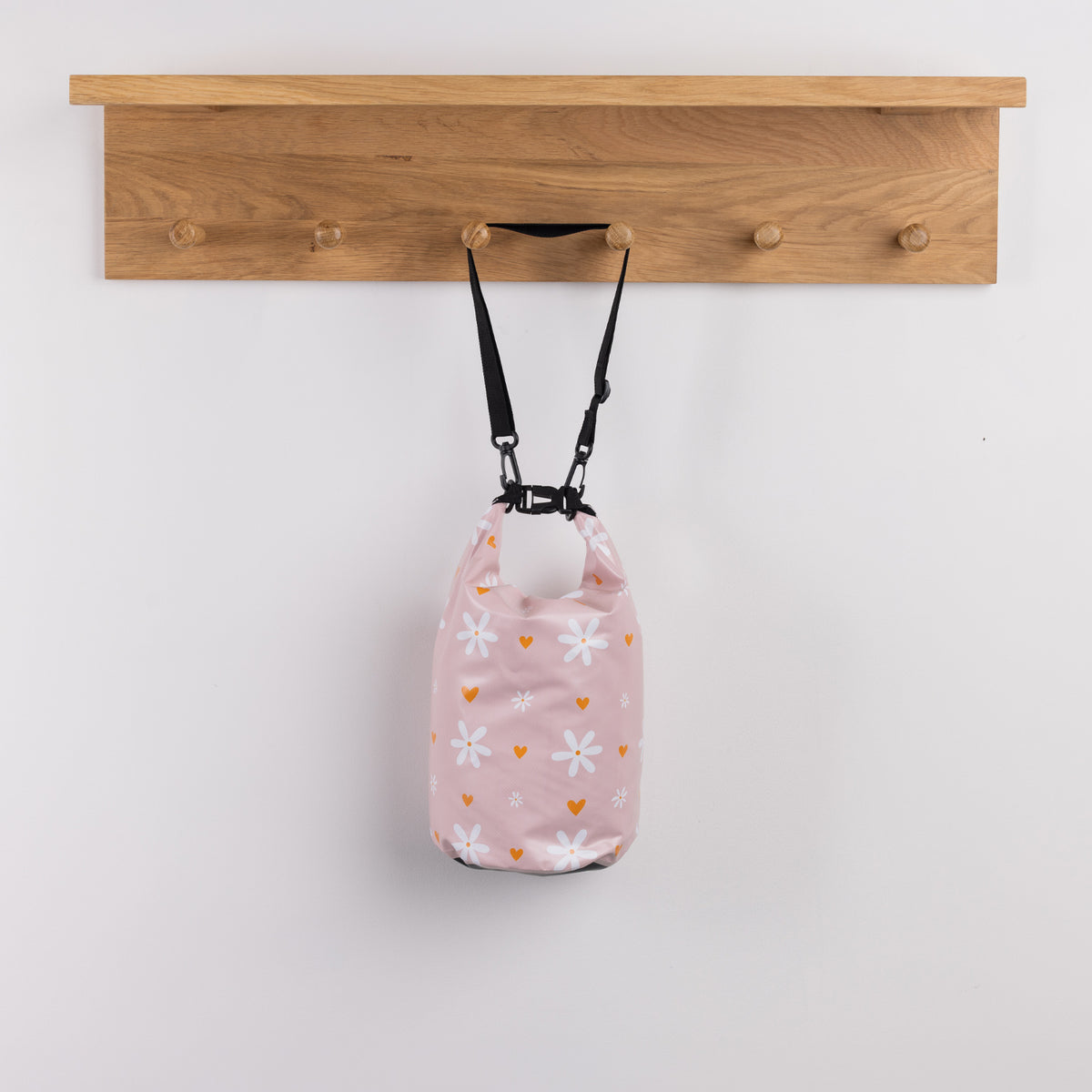 Seaside Supplies Waterproof Beach Bag 5.8L Flowers Peach featuring a soft peach-pink design with white daisies and small orange hearts, finished with a roll-top closure and black shoulder strap.
