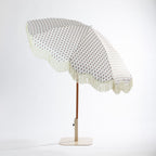 Seaside Supplies floral outdoor umbrella shown at an angle, featuring a cream floral-patterned canopy with scalloped fringe trim, brown pole and cream base.