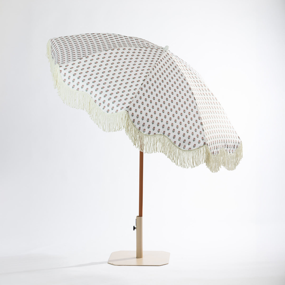 Seaside Supplies floral outdoor umbrella shown at an angle, featuring a cream floral-patterned canopy with scalloped fringe trim, brown pole and cream base.