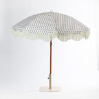 Seaside Supplies floral outdoor umbrella shown front-on with a cream patterned canopy, scalloped fringe trim, brown pole and cream base.