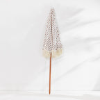 Seaside Supplies Floral Beach Umbrella featuring a cream canopy with a delicate floral print, cream fringed edges and a brown pole, displayed folded against a white background.
