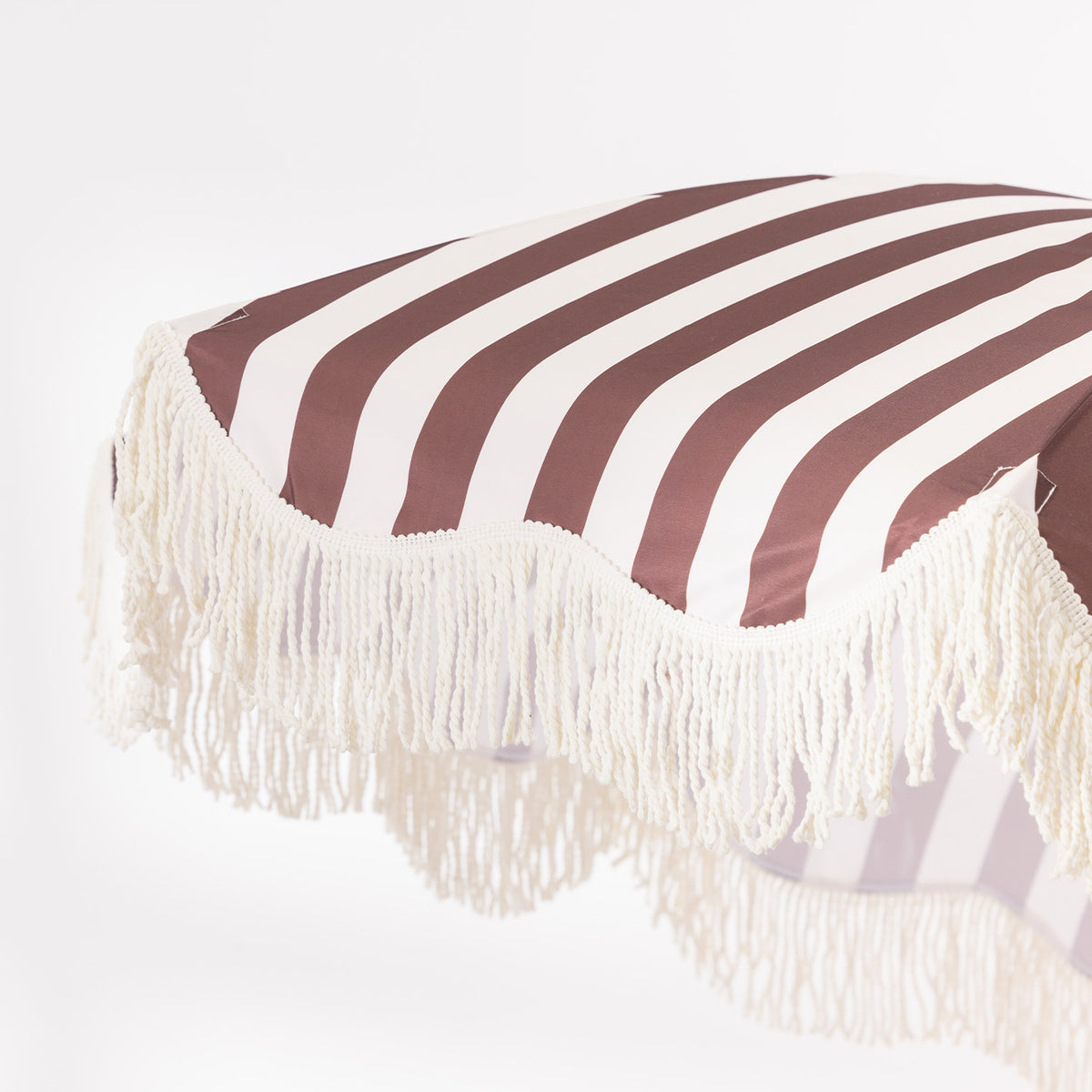 Close-up of the brown and white striped umbrella canopy showing the bold stripe design and cream fringe trim.