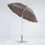 Seaside Supplies Chocolate Beach Umbrella shown open and tilted, revealing the chocolate-brown underside, white support ribs and adjustable pole against a white background.