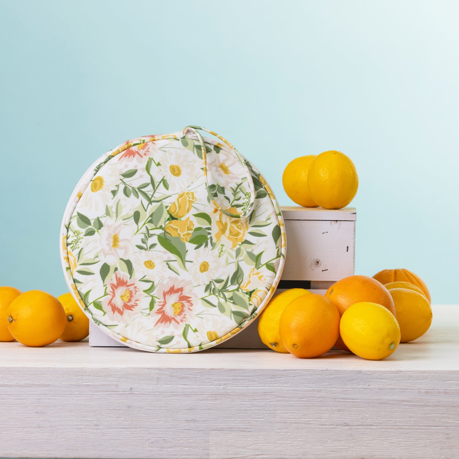 A round  2 person picnic set on a white wooden table, styled with lemons and oranges against a light blue background.