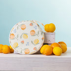 A round  2 person picnic set on a white wooden table, styled with lemons and oranges against a light blue background.