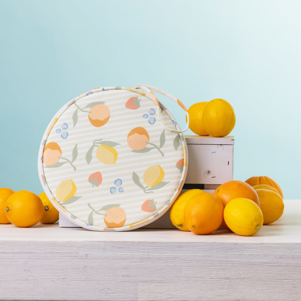 A round  2 person picnic set on a white wooden table, styled with lemons and oranges against a light blue background.