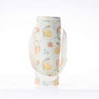 A fruit print bottle bag with a white strap stands against a white background.