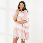 A woman wearing a classic stripe hooded beach poncho with fringed tassels along the hem, photographed against a clean white studio background.