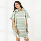 A woman wearing a classic stripe hooded beach poncho with fringed tassels along the hem, photographed against a clean white studio background.