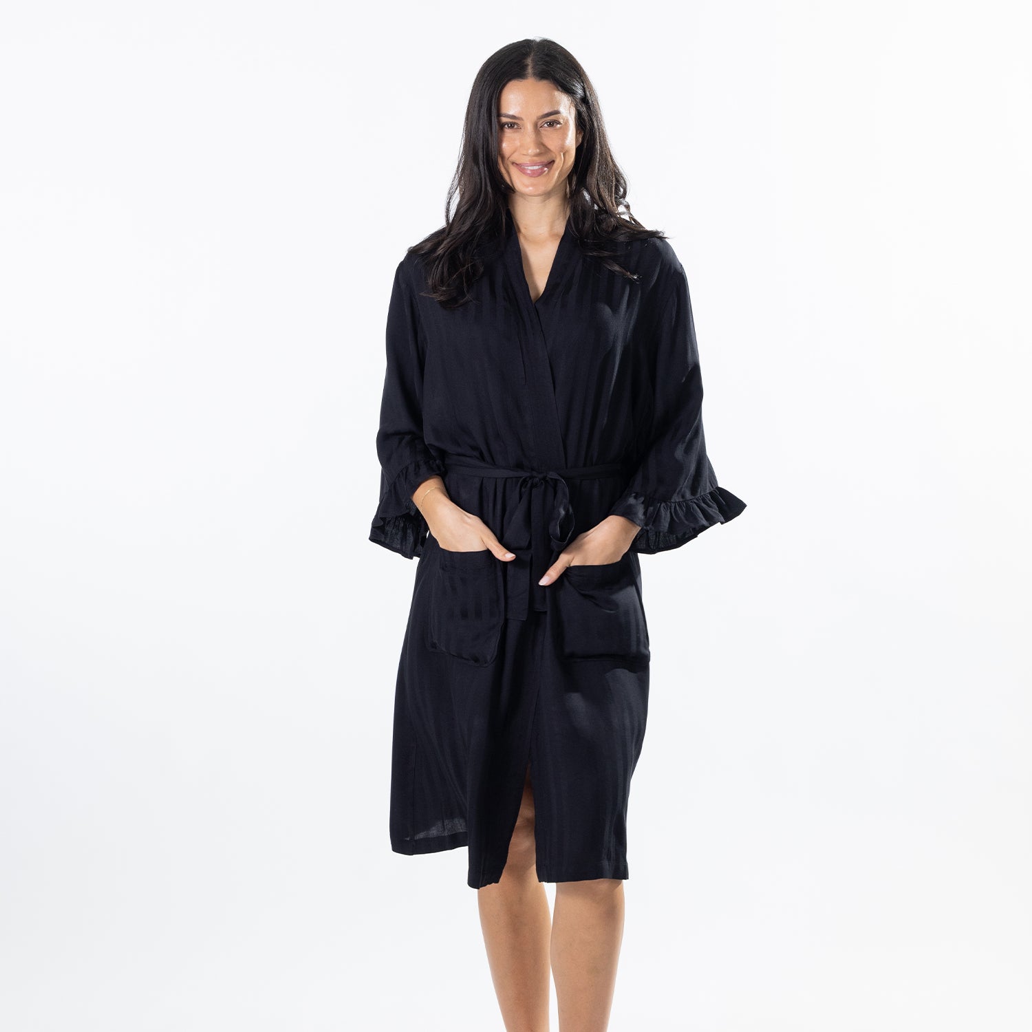 A woman modeling a black robe with wide ruffled sleeves, a tie waist belt, and front patch pockets against a plain white studio background.