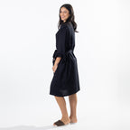A woman modeling a robe with lace shoulder details, a tie waist belt, and side pockets, paired with brown slide sandals against a white studio background.