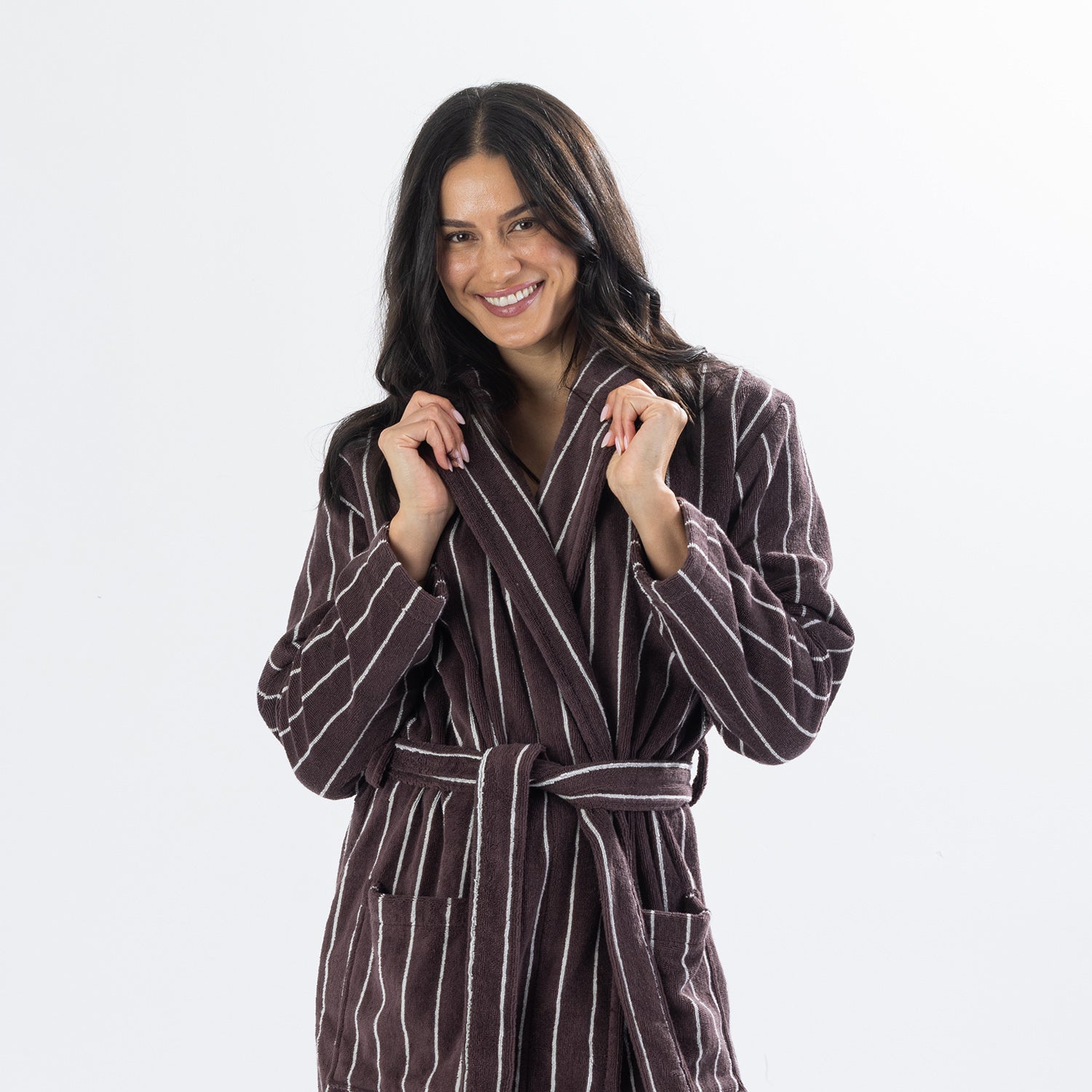 Close-up of a woman wearing a chocolate brown striped towelling robe, holding the shawl collar to showcase the soft towelling fabric.