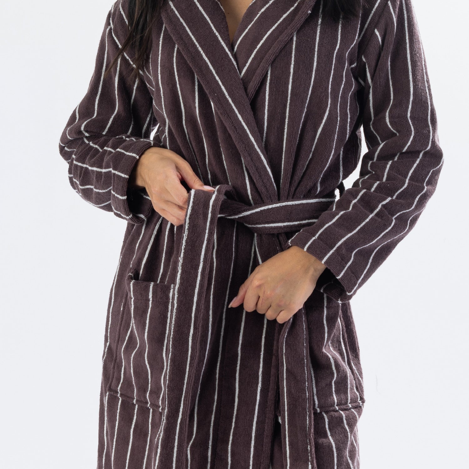Close-up of a chocolate brown striped towelling robe showing the tie belt, shawl collar, long sleeves and front patch pockets.