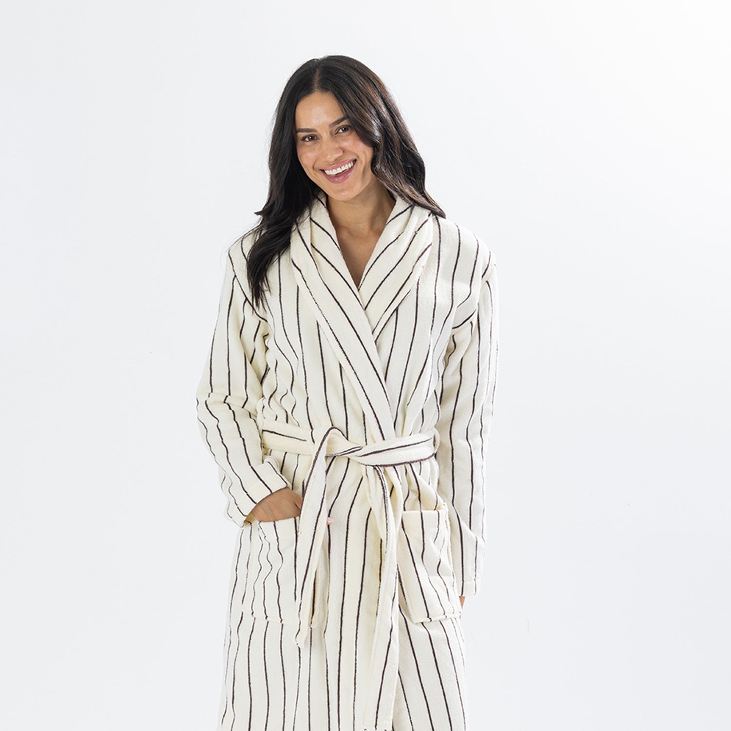 Woman wearing a natural striped towelling robe, smiling in a three-quarter view, highlighting the shawl collar and relaxed fit.