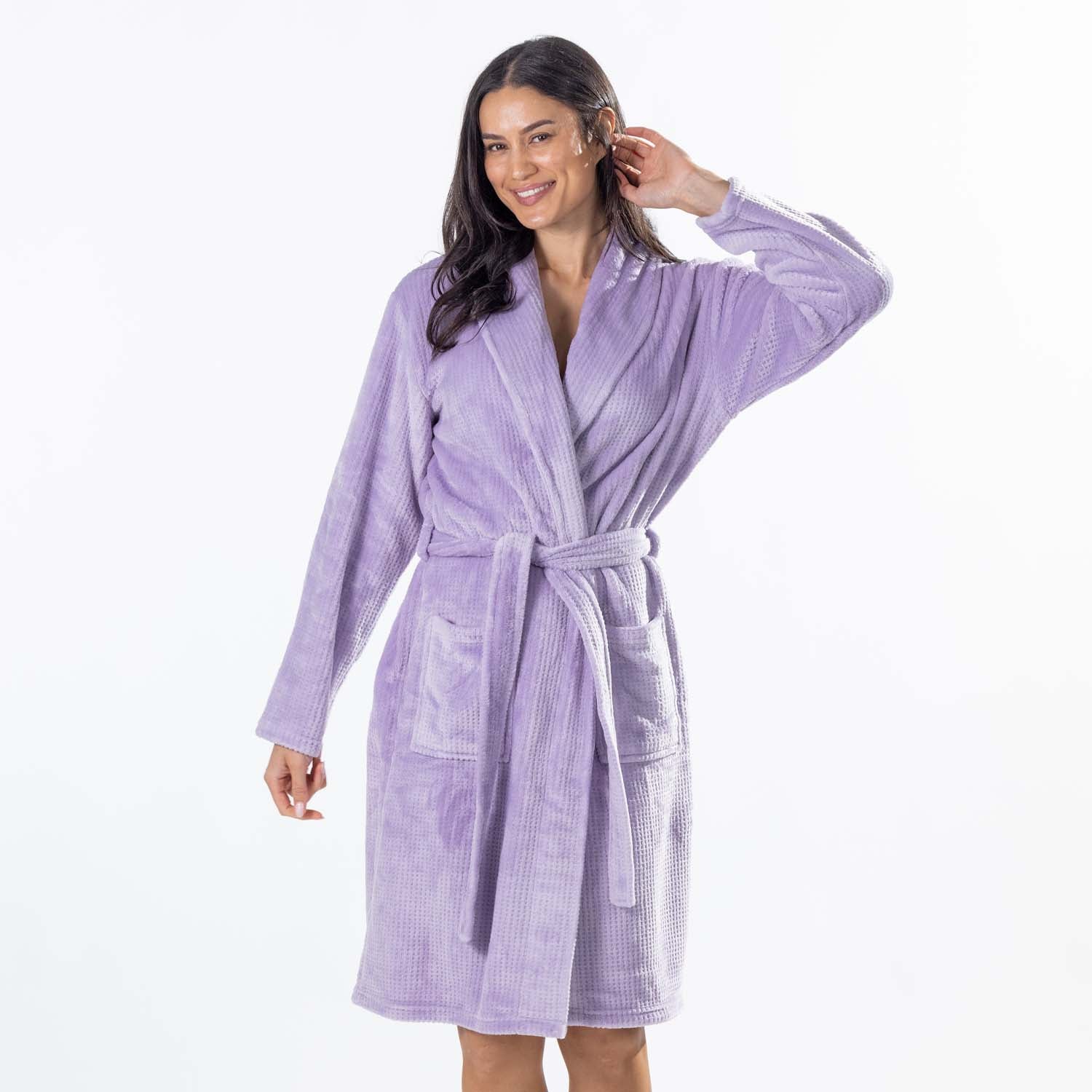 A woman modeling a light purple waffle-textured bathrobe with a tie belt and front pockets, set against a plain white studio background.