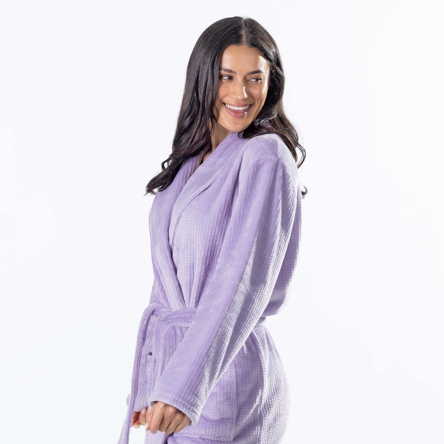 A woman wearing a light purple waffle  bathrobe, photographed against a clean white studio background.