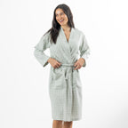A woman models a soft sage green gingham robe featuring a wrap-front design, waist tie and roomy patch pockets.