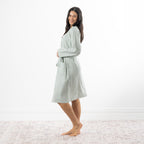 A woman models a soft sage green gingham robe featuring a wrap-front design, waist tie and roomy patch pockets.
