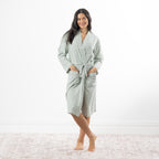 A woman models a soft sage green gingham robe featuring a wrap-front design, waist tie and roomy patch pockets.
