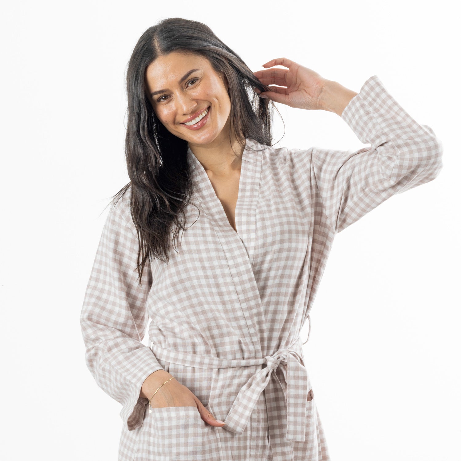 A smiling woman with long dark hair models a light natural and white gingham check robe with a tie belt, set against a plain white background.