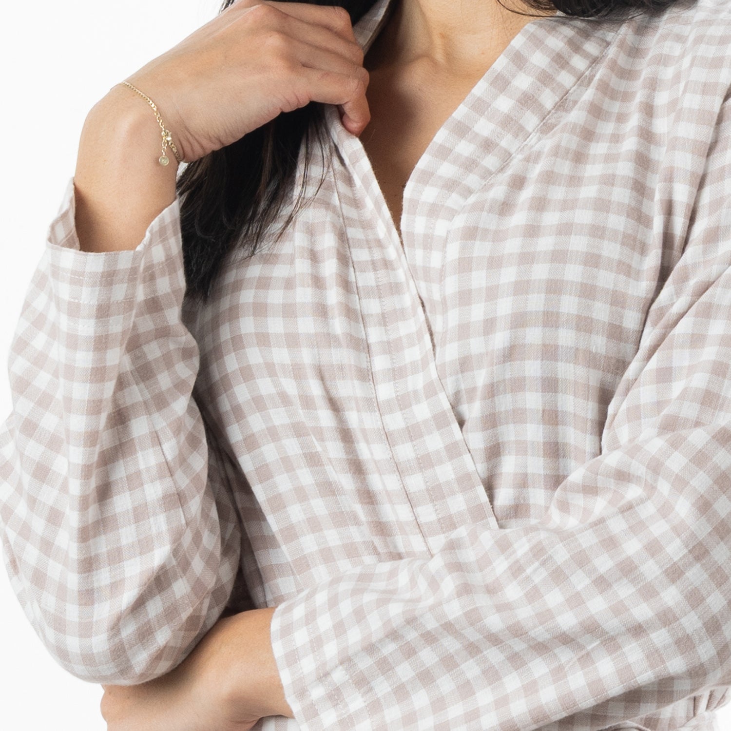 A close-up of a person wearing a light natural and white gingham long-sleeve wrap robe. 