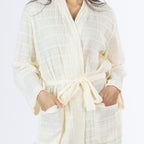 Close-up of the ivory textured stripe robe showing the lightweight crinkled texture, wrap neckline, waist tie and two front patch pockets.