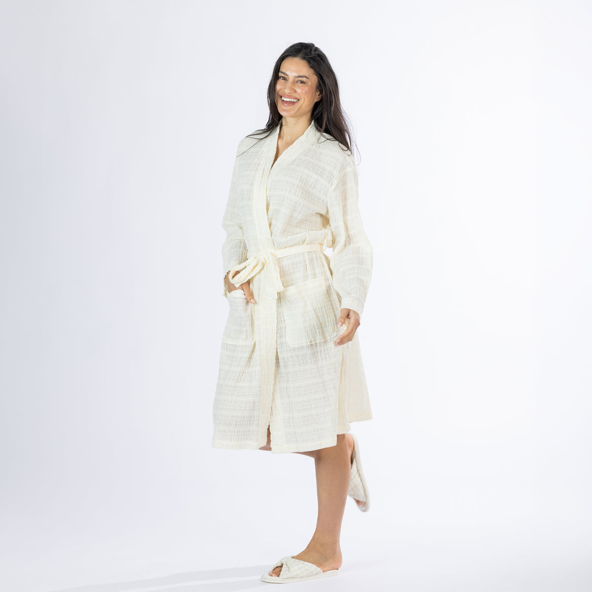Full-length angled view of a model wearing the ivory textured stripe robe with the waist tie fastened and one hand in the front pocket.