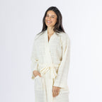 Mid-length front view of a model wearing the ivory textured stripe robe, highlighting the wrap neckline, textured fabric, waist tie and patch pocket.