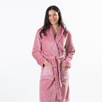 A woman wearing a plush pink waffle-textured bathrobe, standing against a solid white background.