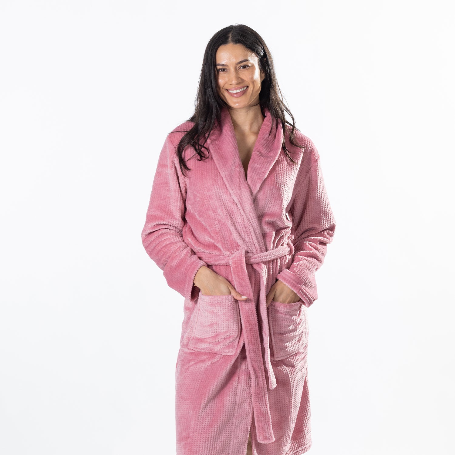 A woman wearing a plush pink waffle-textured bathrobe, standing against a solid white background.