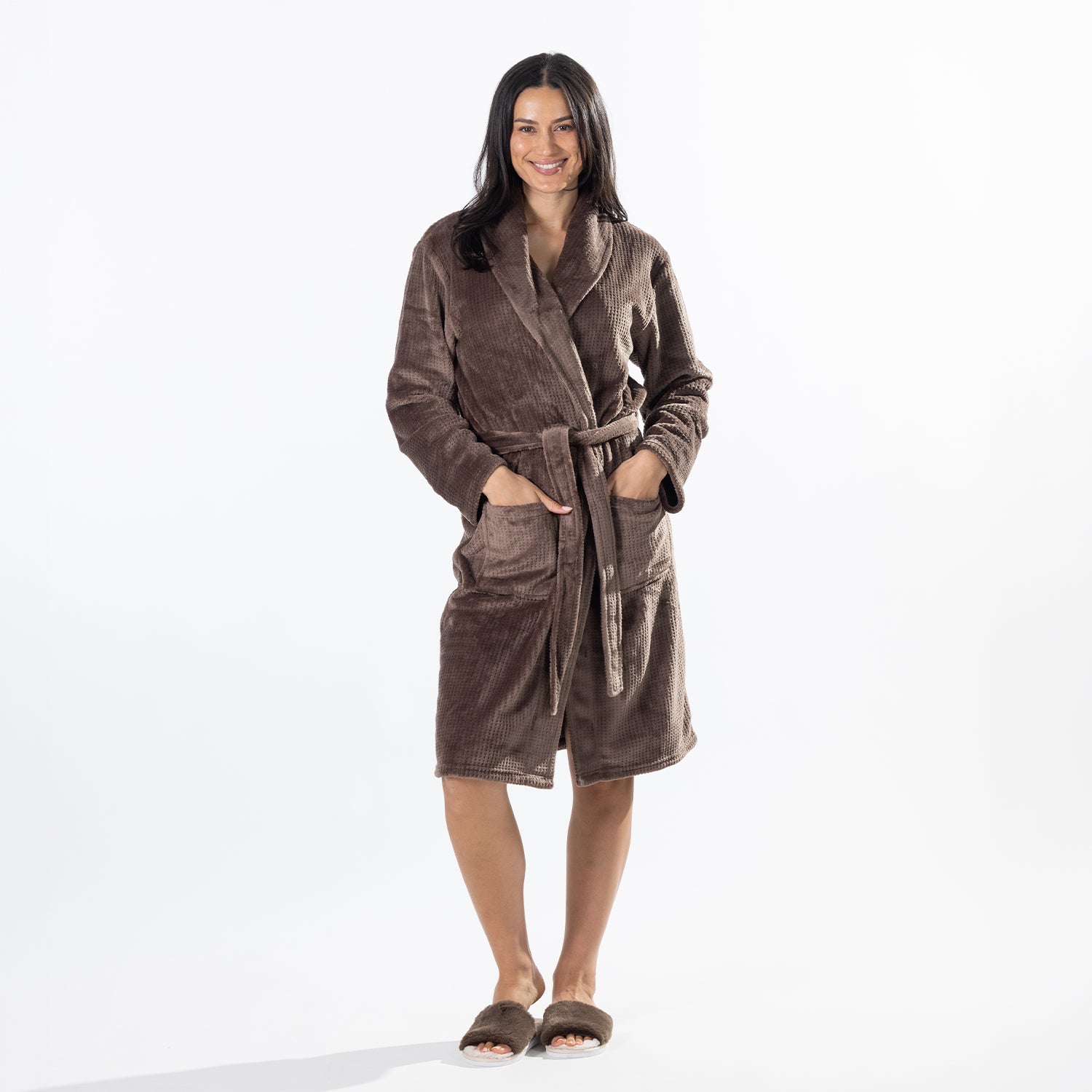 A woman modeling a brown waffle bathrobe against a plain white studio background.