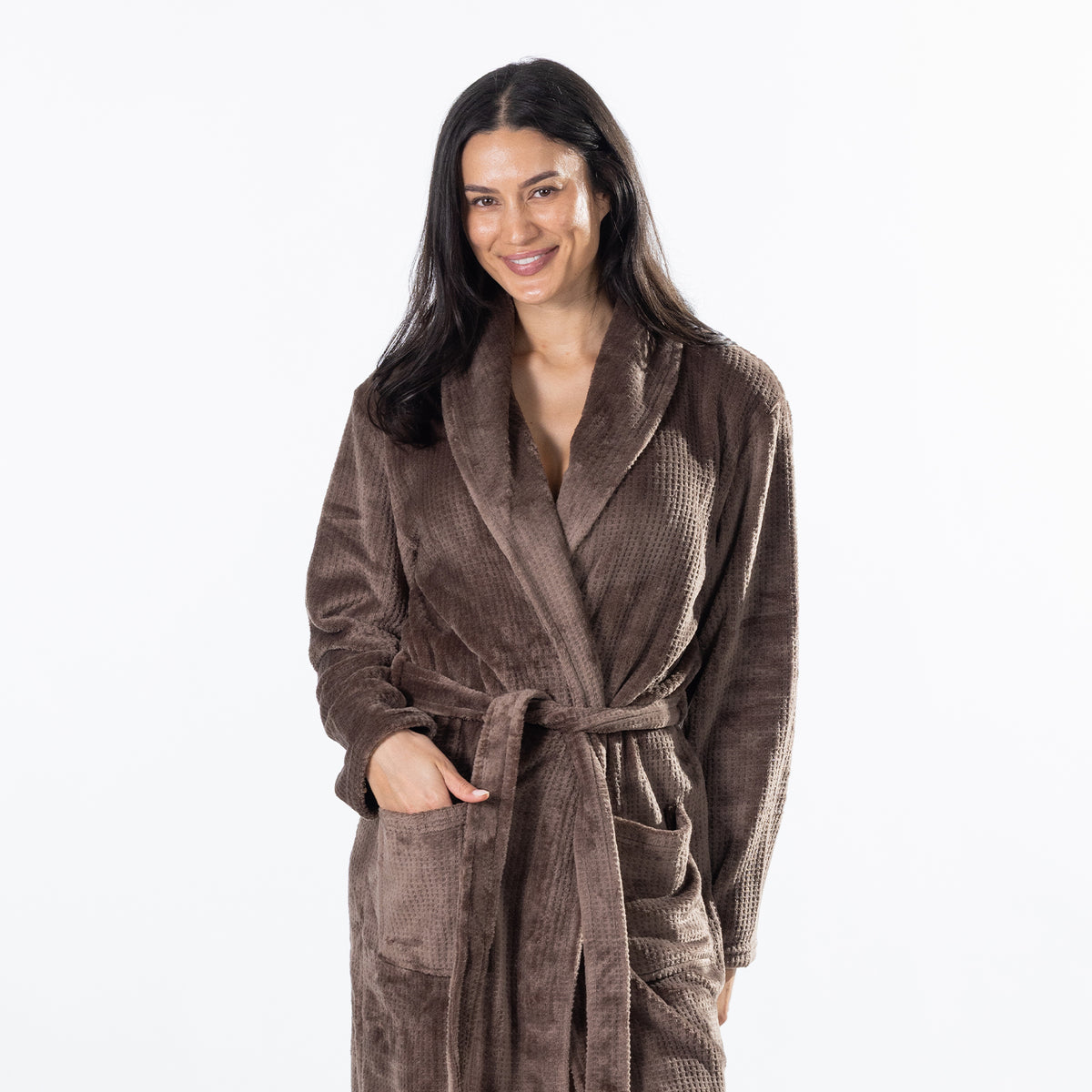 A woman modeling a brown waffle bathrobe against a plain white studio background.