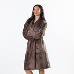 A woman modeling a brown waffle bathrobe against a plain white studio background.