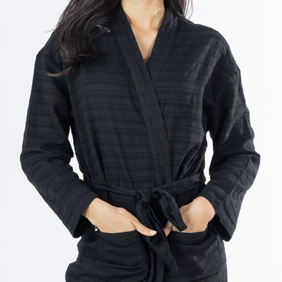 Close-up of the black textured bathrobe showing the subtle stripe texture, wrap neckline, waist tie and front pocket detail.