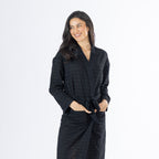Mid-length front view of a model wearing the black textured bathrobe, highlighting the relaxed fit, long sleeves, textured fabric and front pockets.